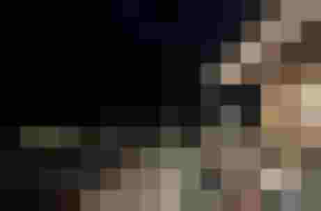 Holzterrasse einer Almhütte bei Nacht mit Blumen und stimmungsvoller Beleuchtung