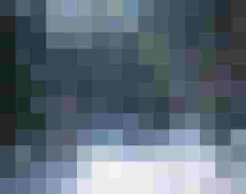 verschneite Waldstraße mit Sonne über schneebedeckten Fichten