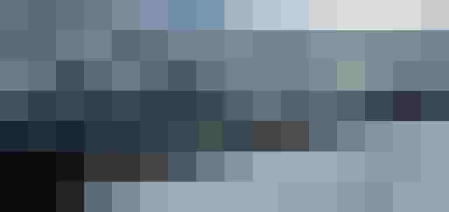 Verschneiter Hang mit Fußspur vor bewaldetem Hang und felsigem Bergmassiv unter bewölktem Himmel