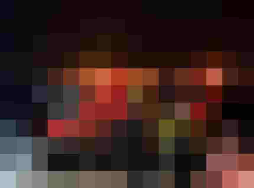 Gruppe steigt nachts auf schneebedecktem Platz in einen beleuchteten roten Pistenbully ein